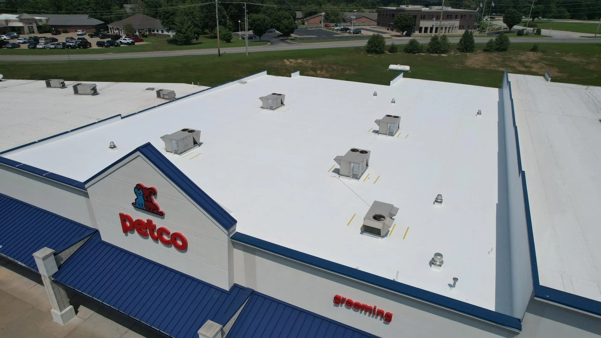 White TPO flat roof with blue trim, HVAC units, and metal flashing on commercial building