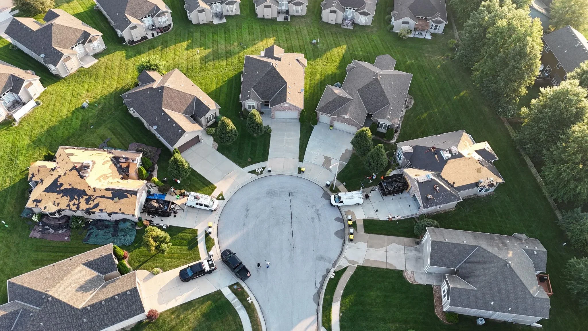 Aerial view of residential homes with new asphalt shingle roofing installation and exposed roof decking